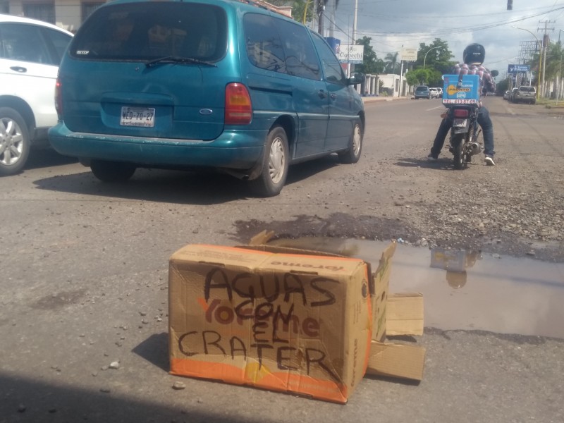 Comerciantes alertan a conductores por baches