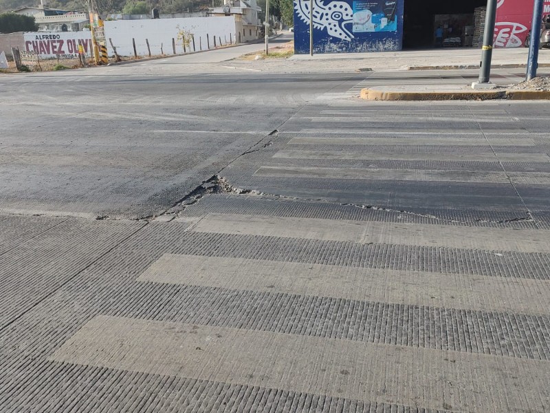 Acceso principal con baches y cuarteaduras; necesita rehabilitación