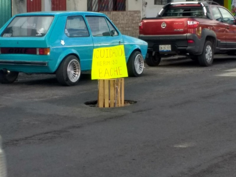 Con letrero exigen reparar enorme bache