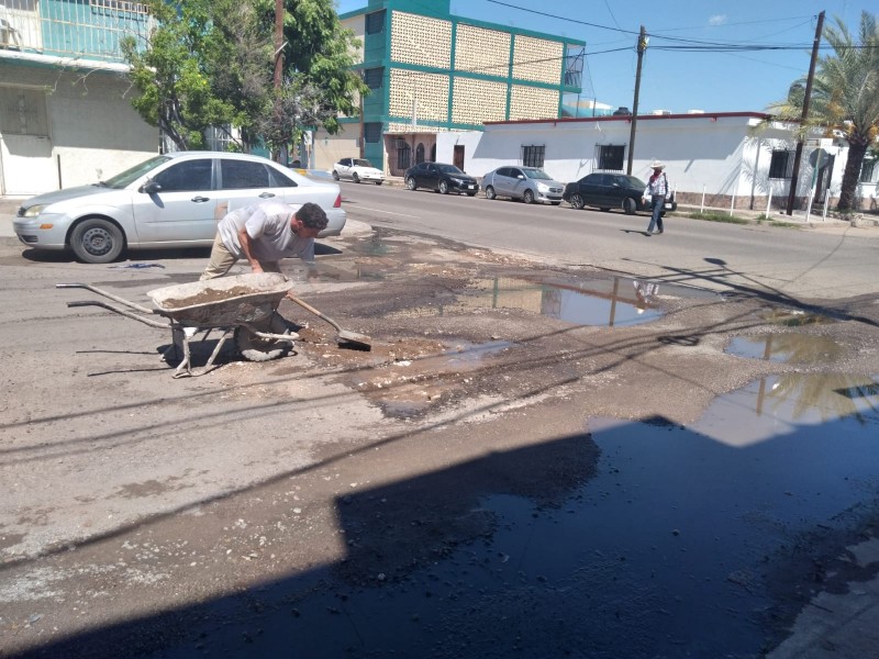 Familia hermosillense tapa baches afuera de su casa