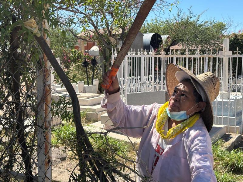 Francisca Olpidena limpia la tumba de familiares, previo al Día de Muertos