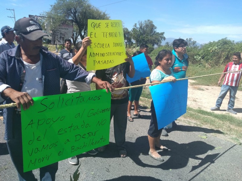 Padres de bachillerato bloquean carretera para proteger predio